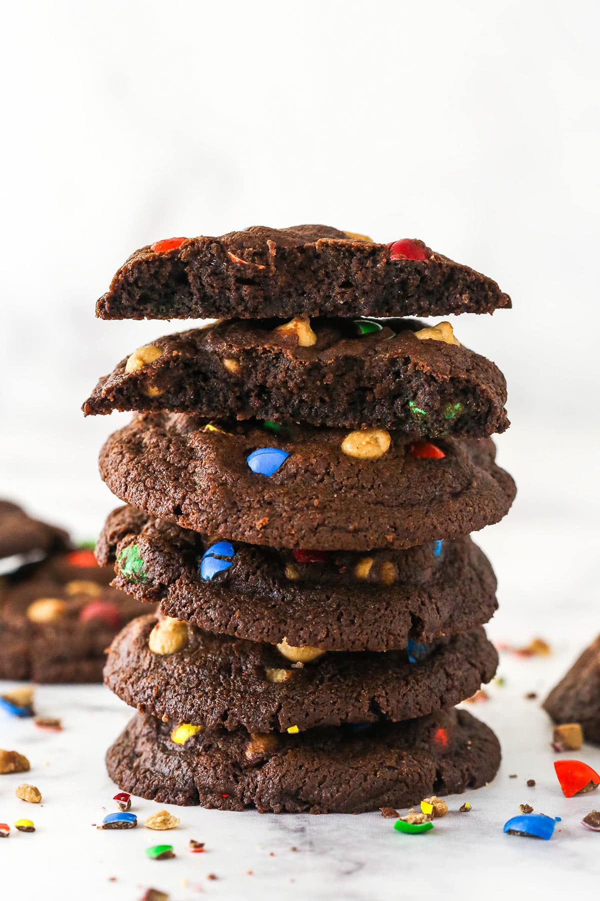 A stack of peanut butter m&m cookies, with two broken in half to show the inside.