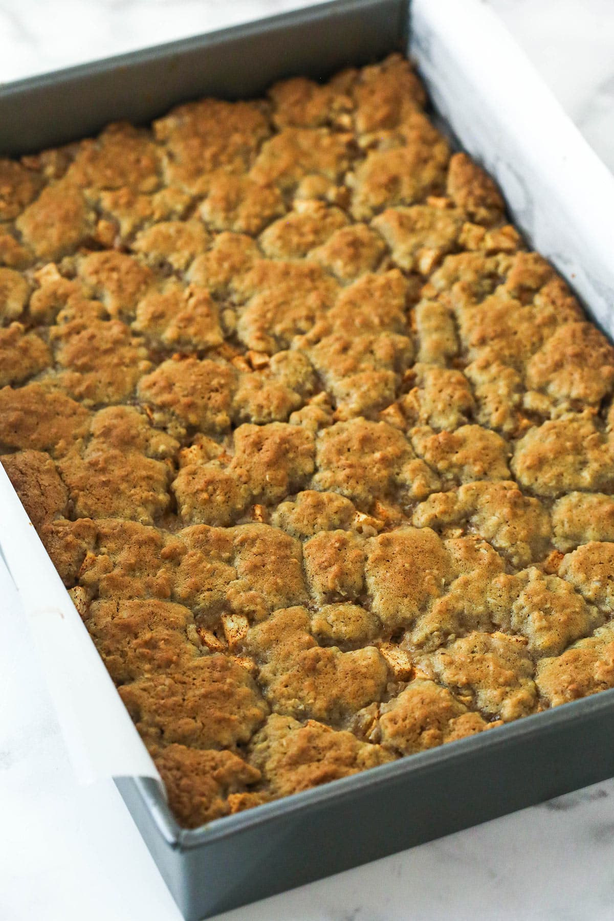 Baked apple cheesecake oatmeal cookie bars in a cake pan