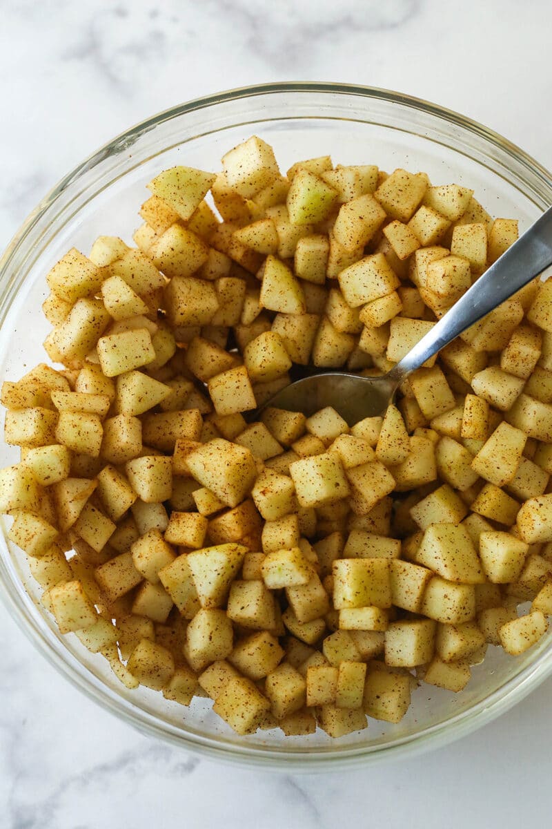 A spoon stirring cinnamon apples