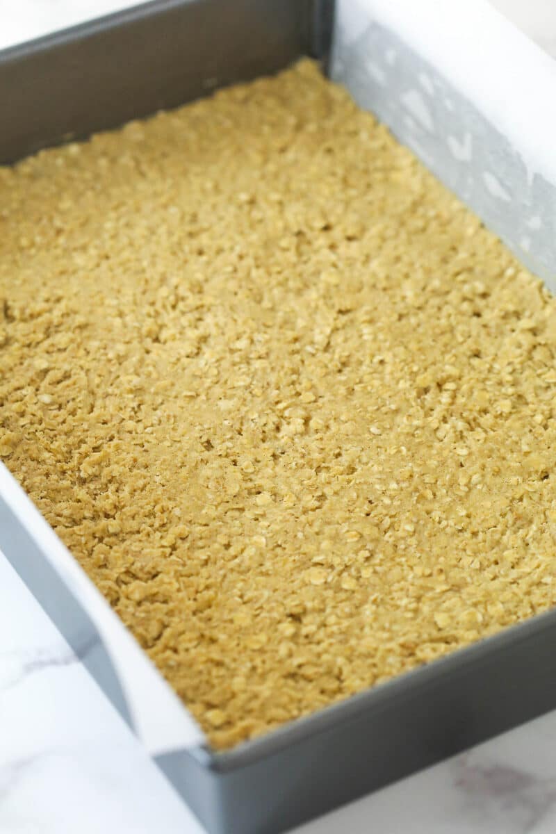 Oatmeal cookie dough pressed into a baking pan