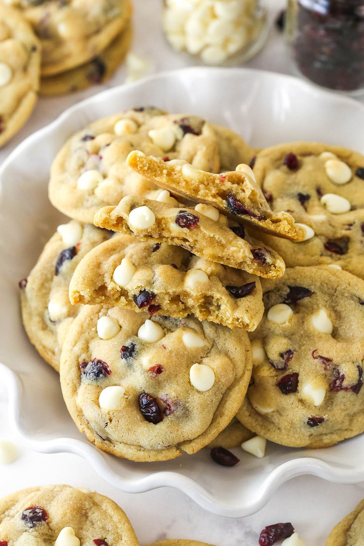 A bowl of cranberry white chocolate cookies with one broken in half to show the inside