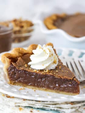 slice of chocolate hazelnut chess pie on a white plate with full pie in background