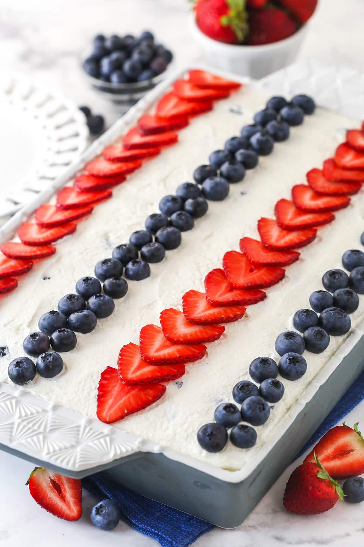 fully decorated berry icebox cake with berries around the pan and a blue napkin underneath