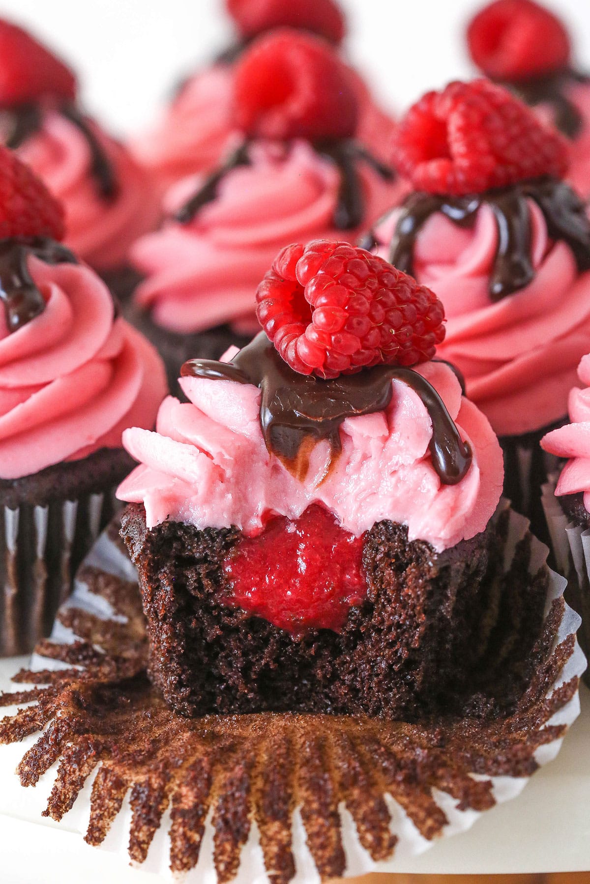 A raspberry chocolate cupcake with a bite missing to show the inside