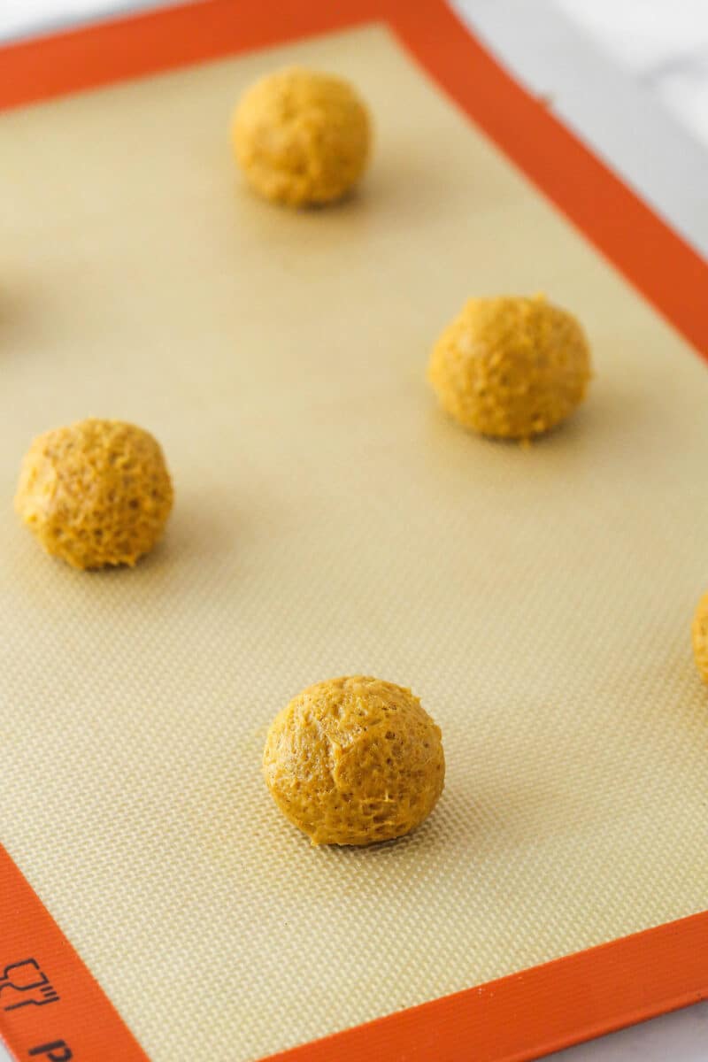 Balls of pumpkin cookie dough on a baking sheet