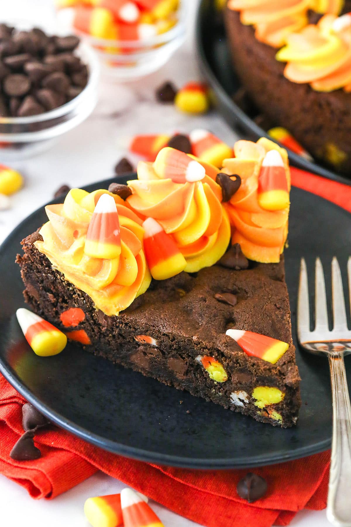 Top view of a slice of Candy Corn Chocolate Chip Cookie Cake on a small black plate.