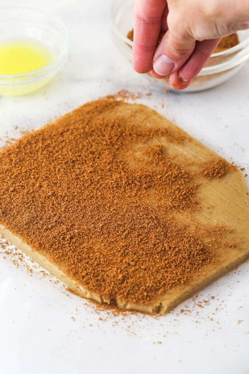 Cinnamon sugar being sprinkled over cookie dough