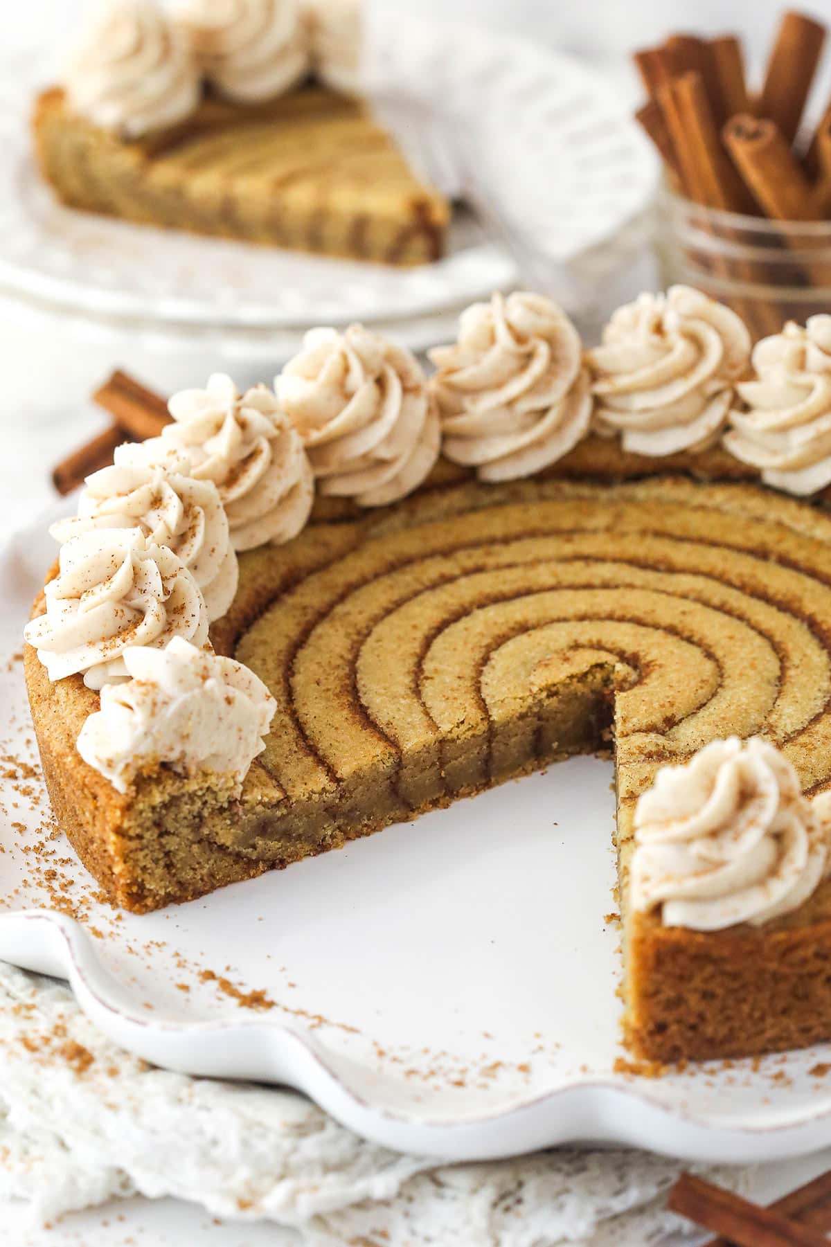 A cinnamon roll cookie cake with a slice missing