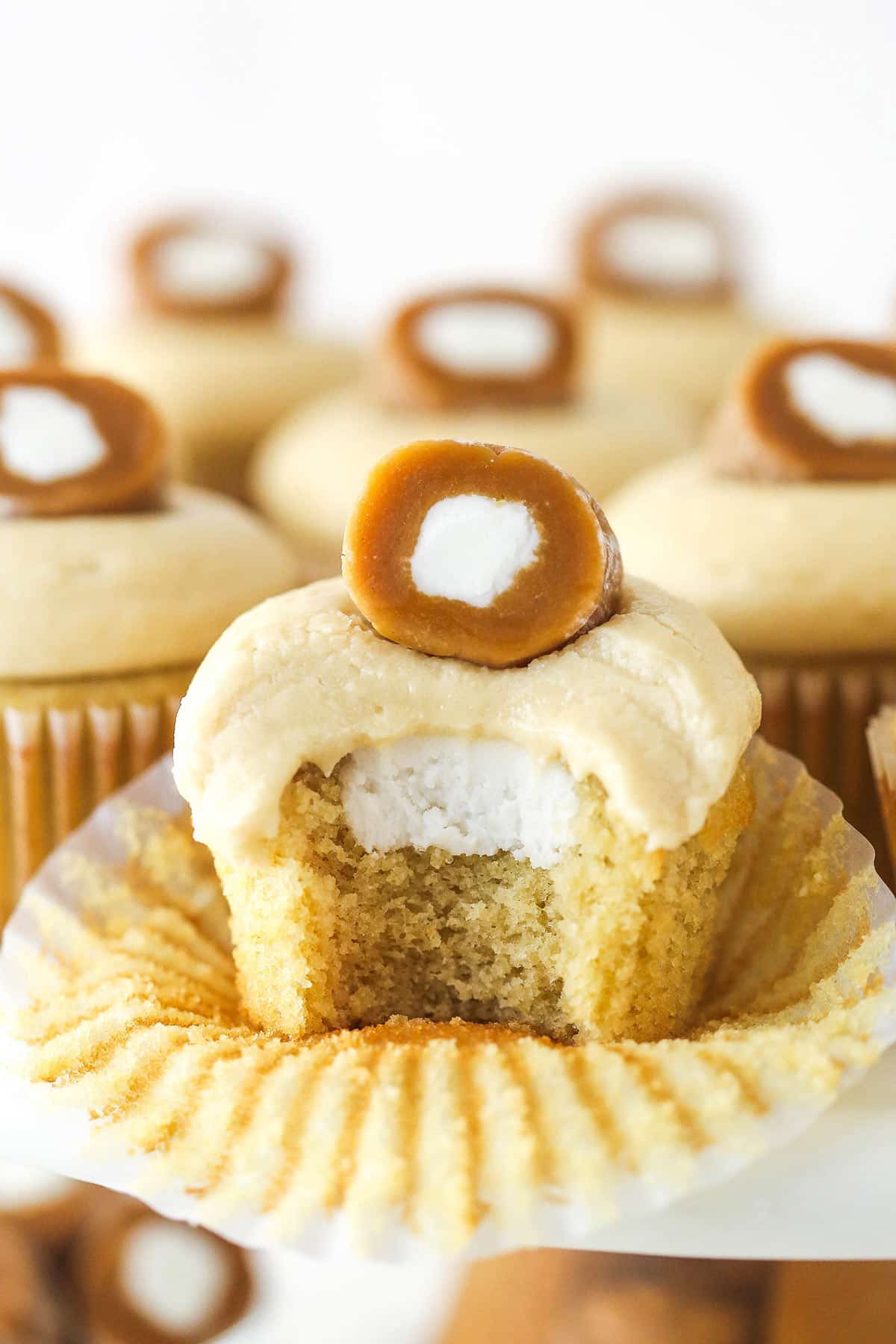 A caramel cream cupcake with a bite missing