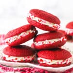 A pile of red velvet cookie sandwiches on a plate