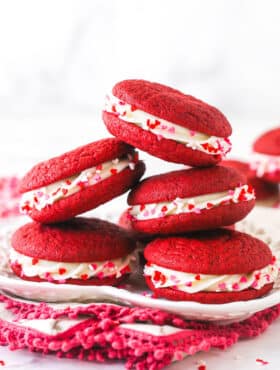 A pile of red velvet cookie sandwiches on a plate