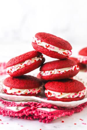 A pile of red velvet cookie sandwiches on a plate