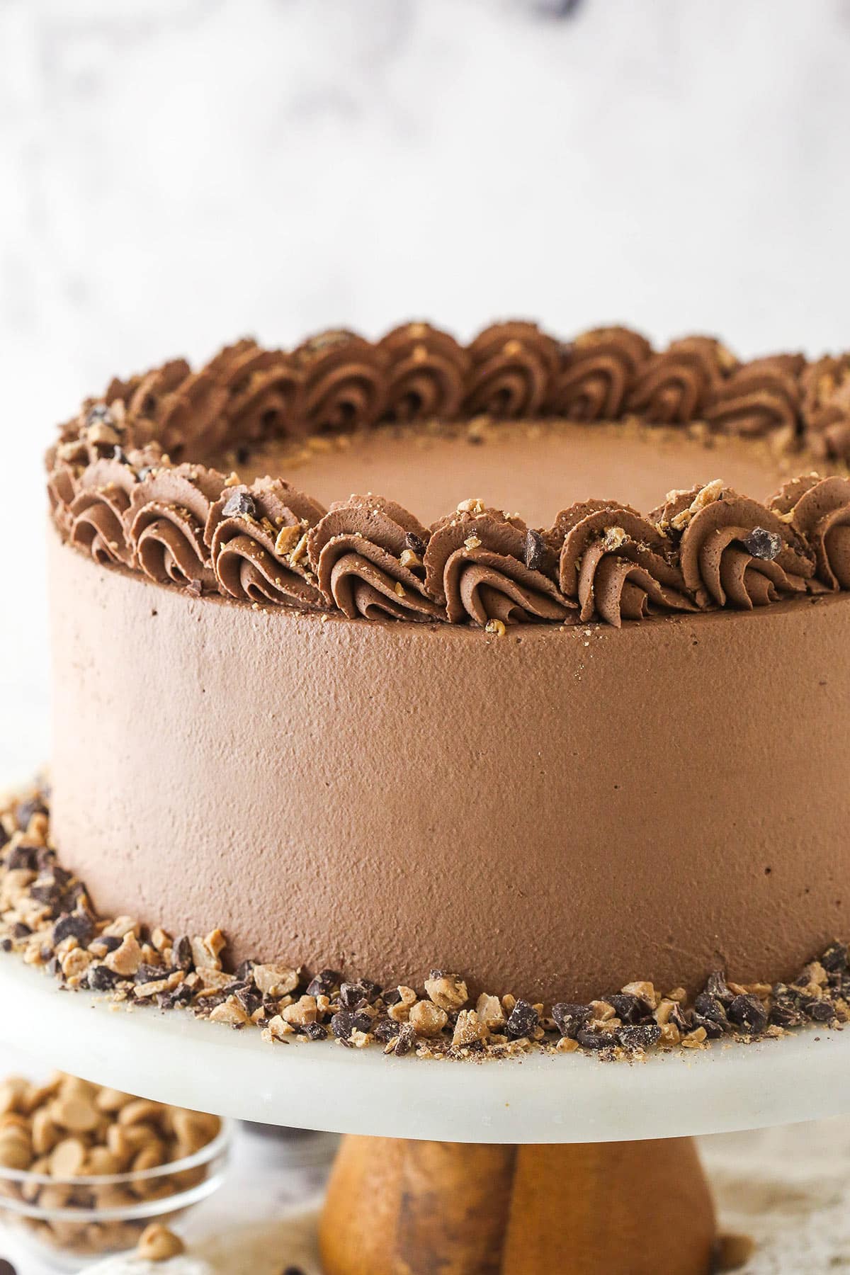 fully frosted peanut butter chocolate mousse cake on marble and wood cake stand