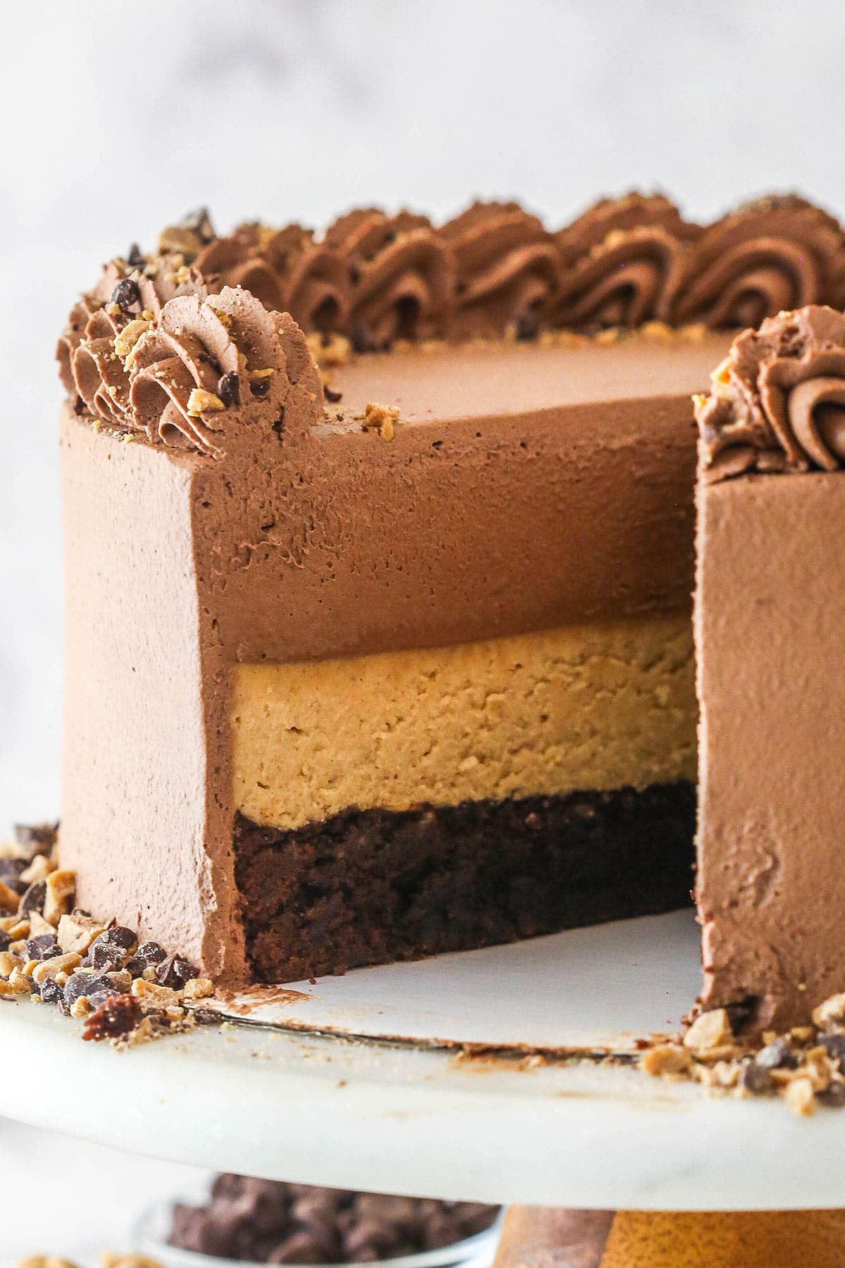 peanut butter chocolate mousse cake with a slice cut out on cake stand