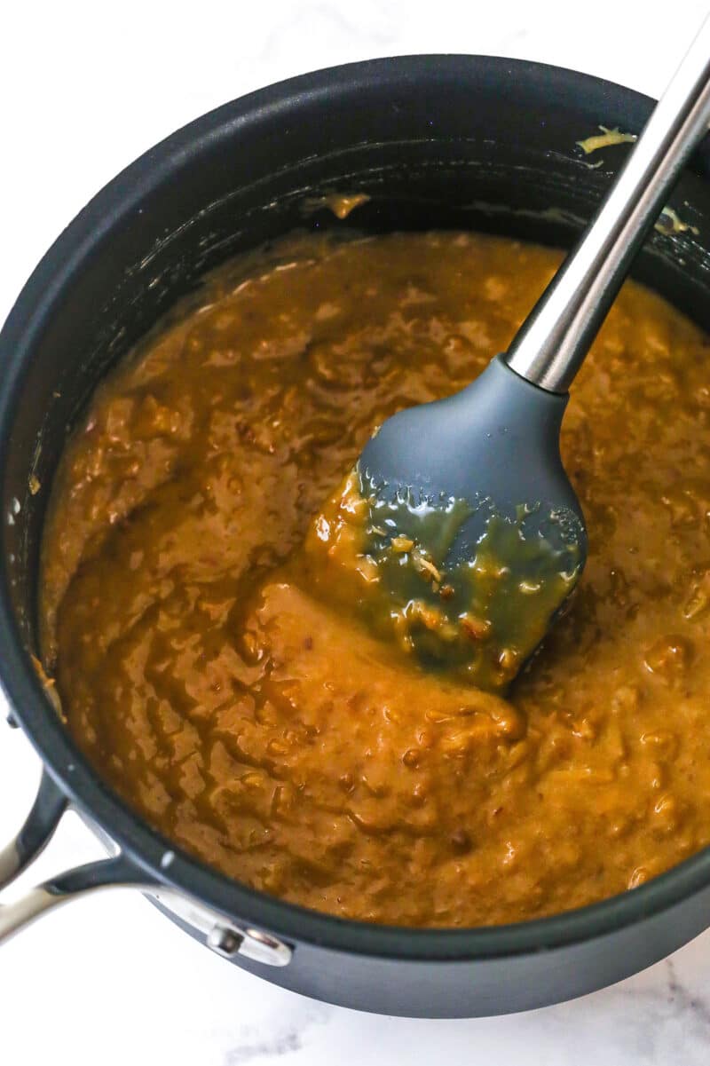 A spatula mixture caramel sauce with toasted coconut