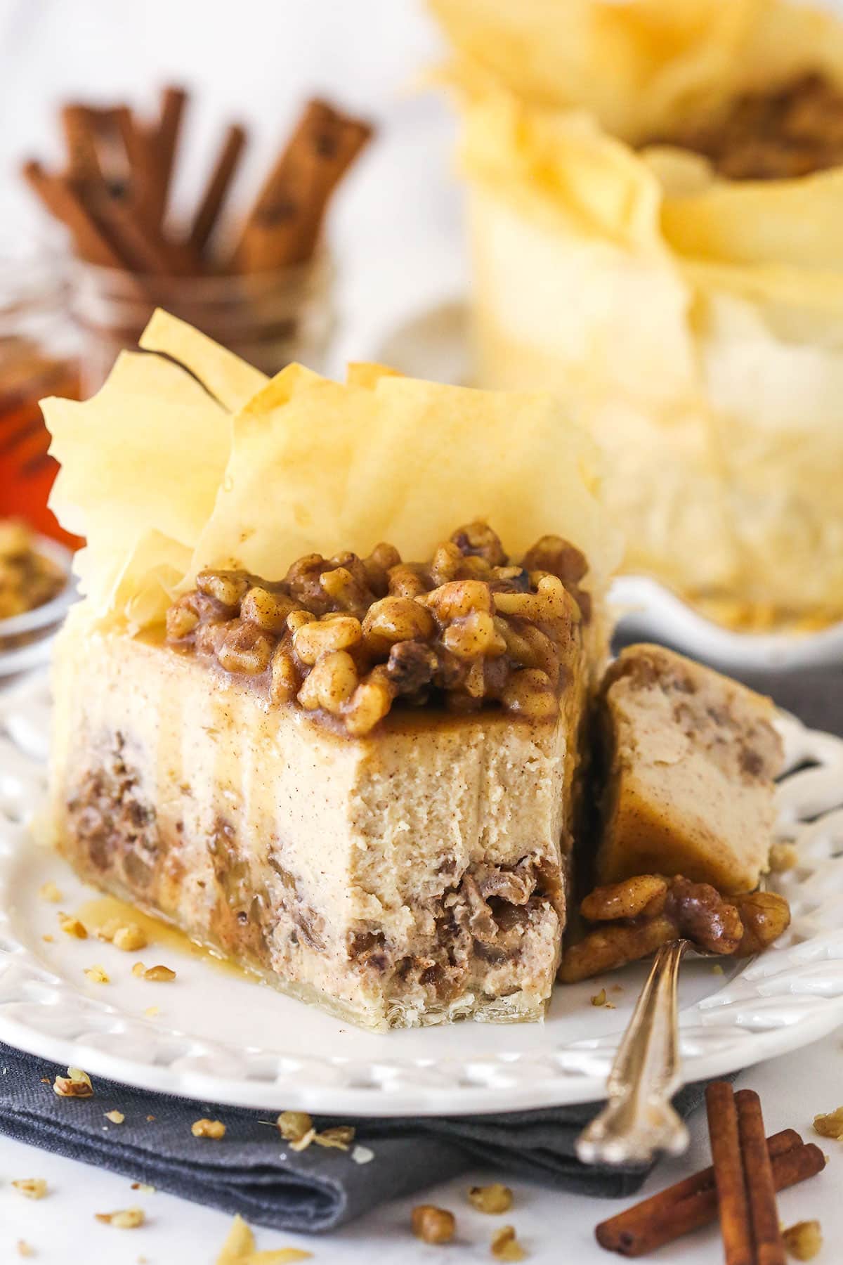 A slice of baklava cheesecake on a plate with a bite on a fork next to it