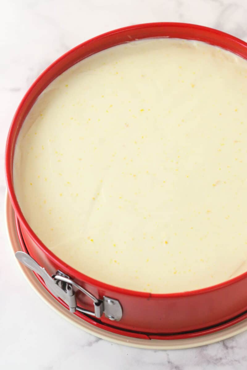 Overhead view of a baked cheesecake in a red springform pan