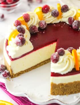 A cranberry orange cheesecake with a slice missing