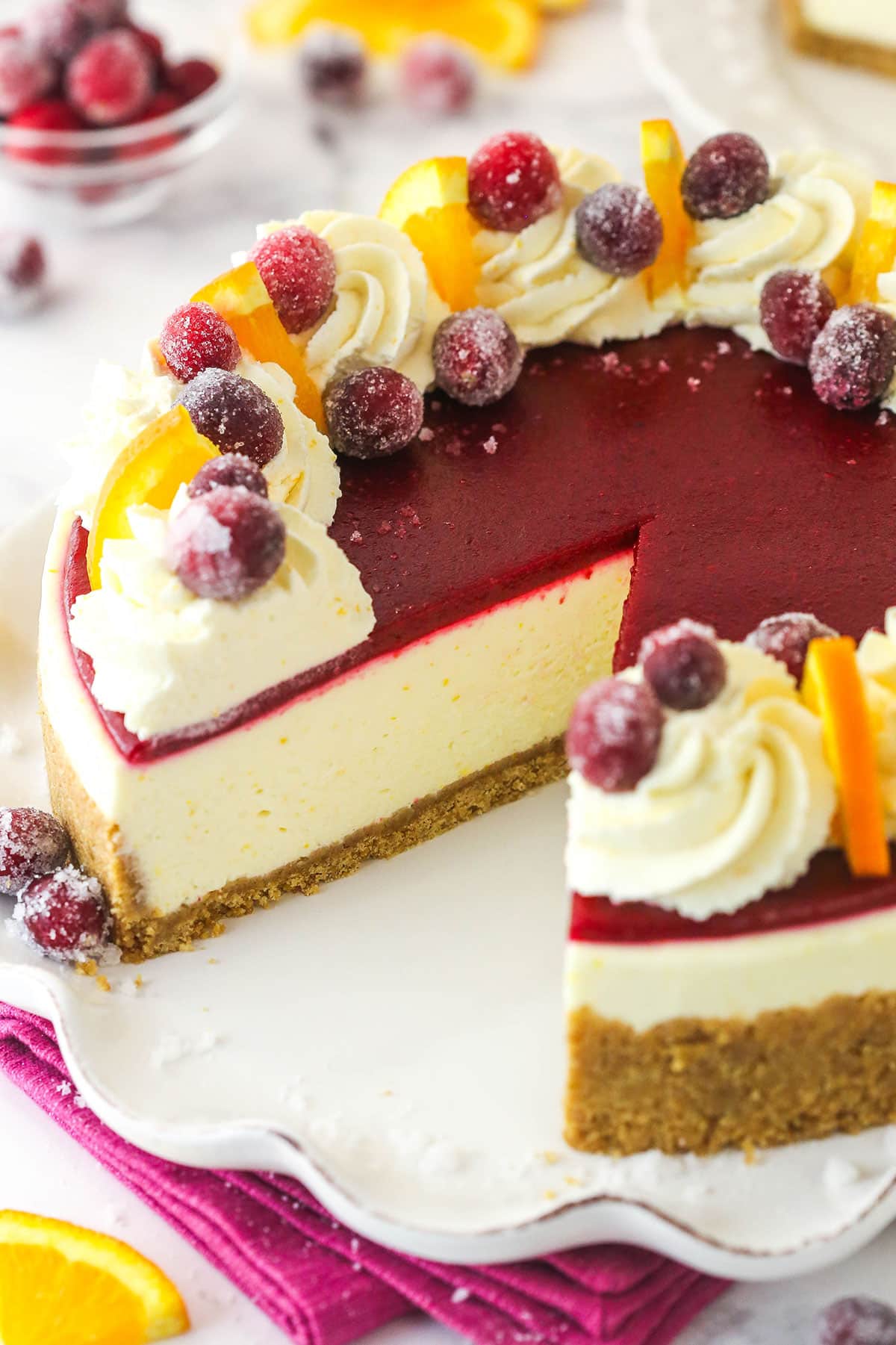 A cranberry orange cheesecake with a slice missing