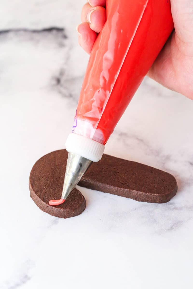 piping a line of royal icing onto a cookie