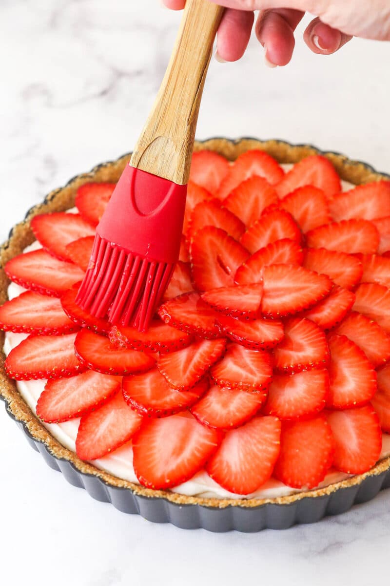 brushing the champagne glaze onto the strawberries on top of the tart