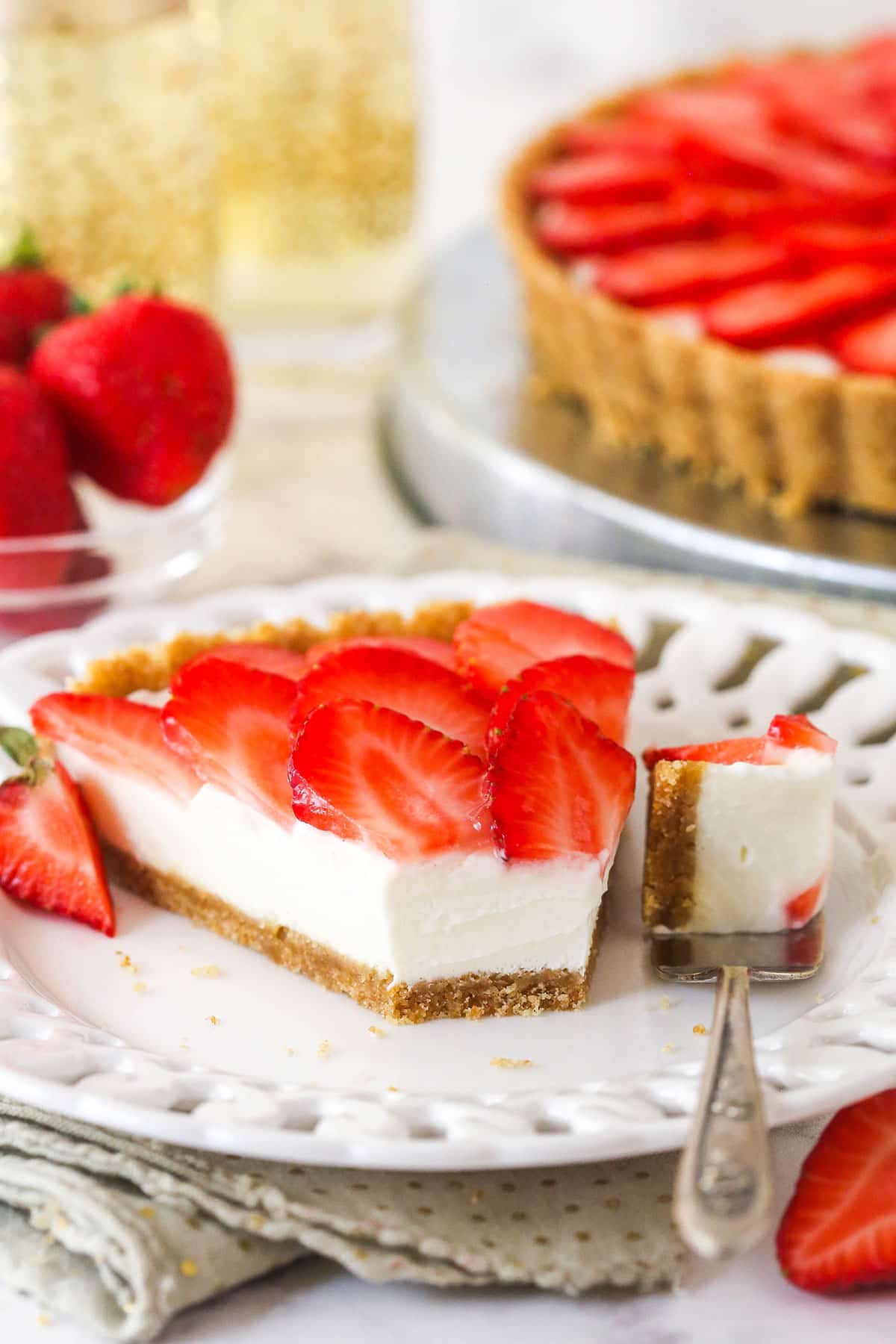 slice of strawberry champagne tart on a white plate with a bite taken