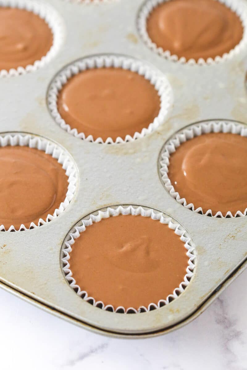 cheesecake batter divided between cups in cupcake pan