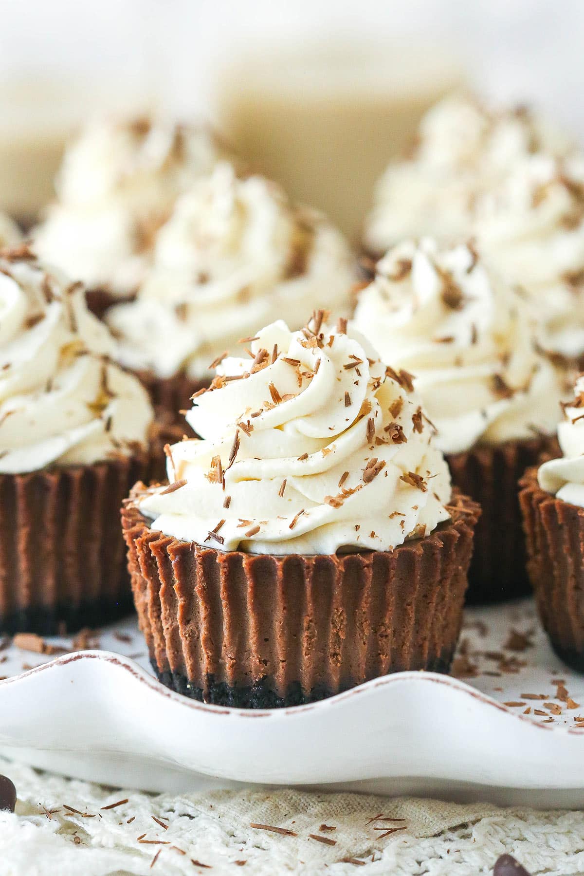 mini baileys chocolate cheesecakes on a white ruffle platter with chocolate shavings