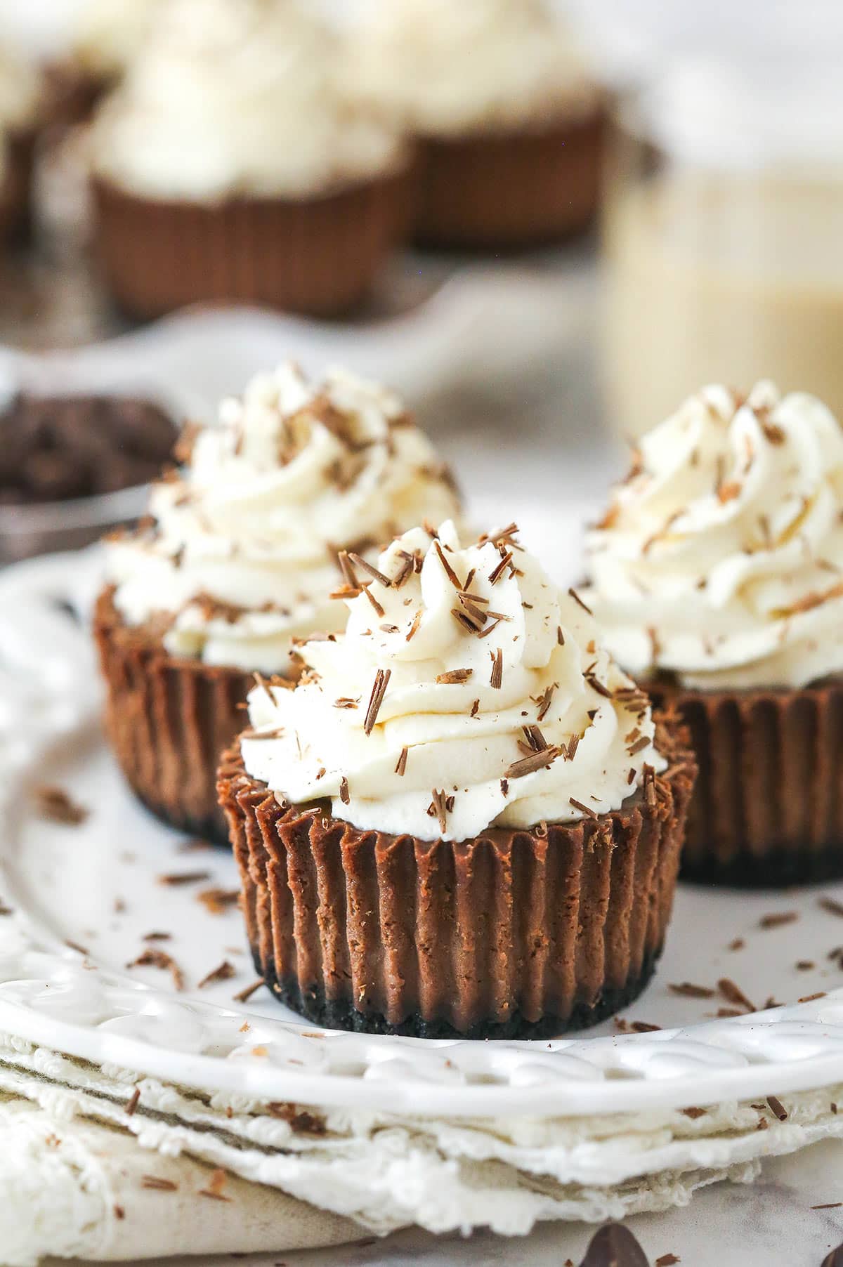 three mini baileys chocolate cheesecakes on a white plate and cream napkin