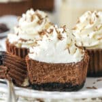 mini baileys chocolate cheesecake on a white plate with a bite taken out