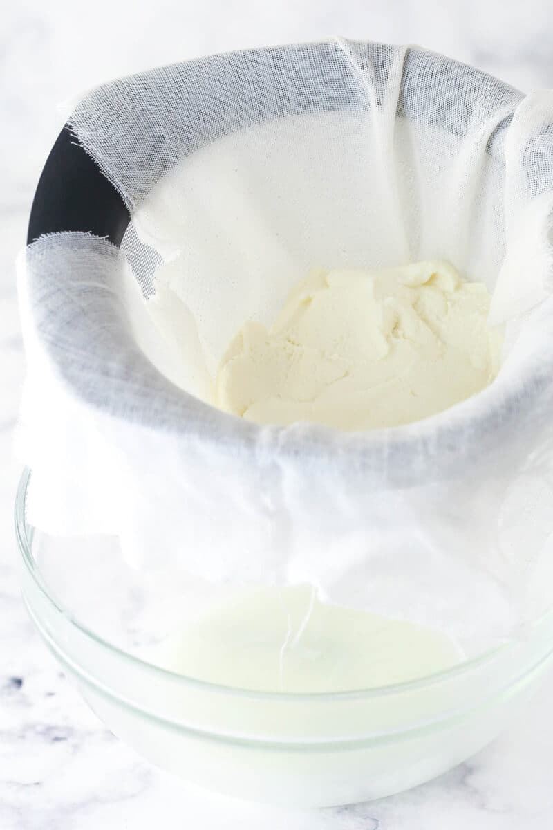 Ricotta cheese being strained through cheesecloth