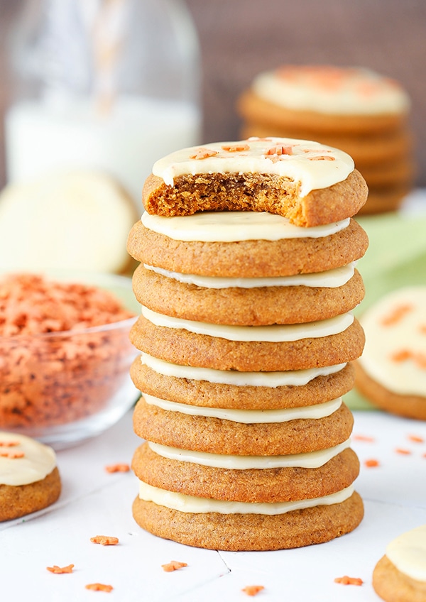 A stack of gingerbread cookies with eggnog icing. The cookie on the top has a bite taken out of it.