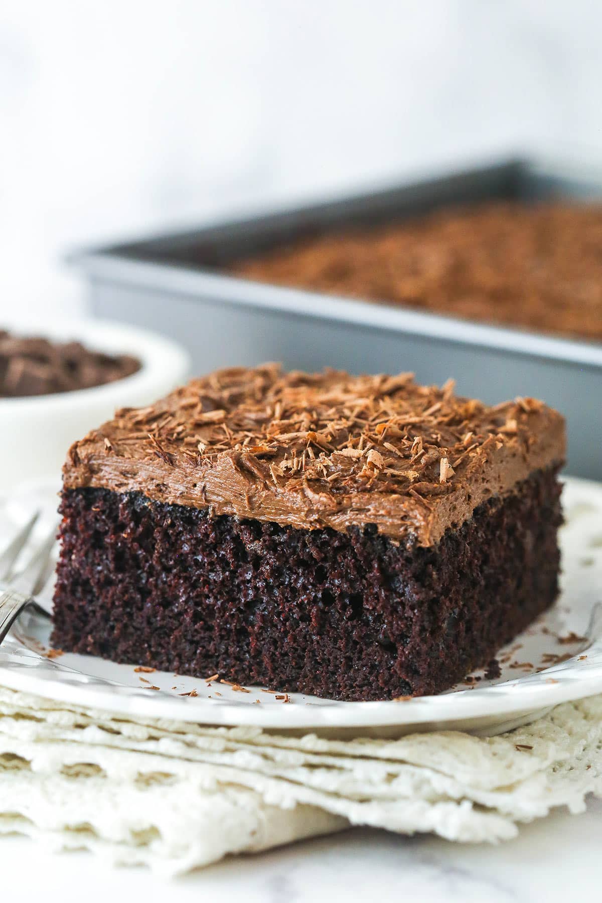 slice of chocolate sheet cake on white plate and cream colored napkin