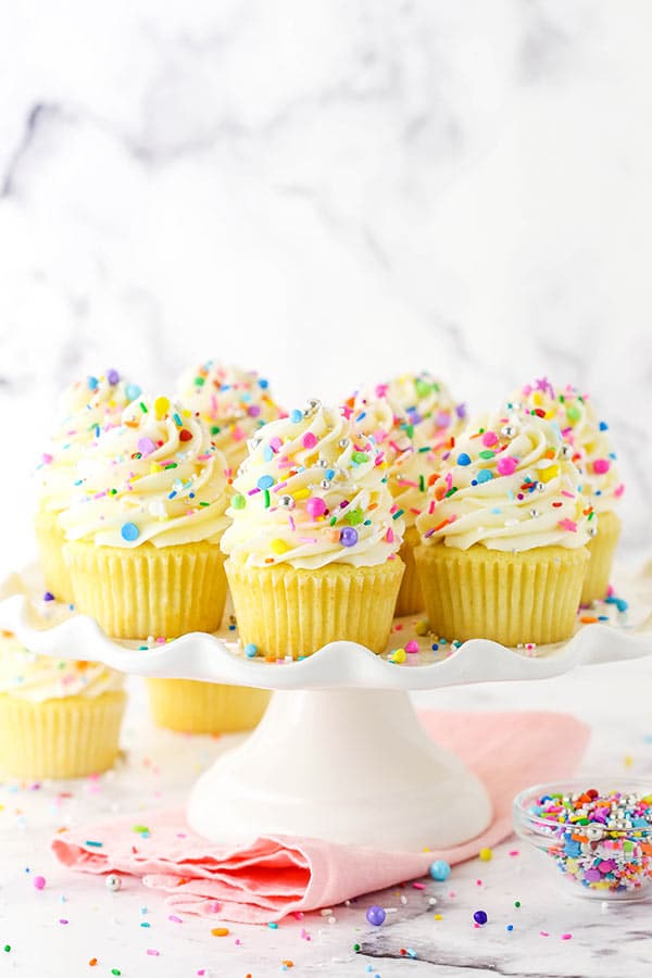 Homemade vanilla cupcakes with sprinkles on a white stand