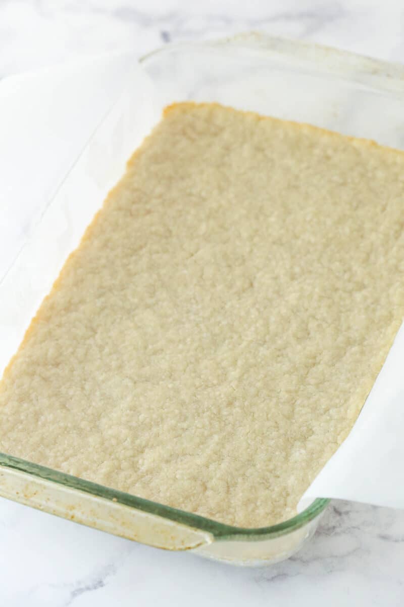 baked crust in a glass pan with parchment overhanging sides