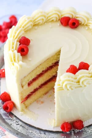 A Raspberry Dream Cake with a slice removed on a silver cake stand