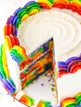 A Rainbow Swirl Cake with a slice removed showing the colorful internal layers