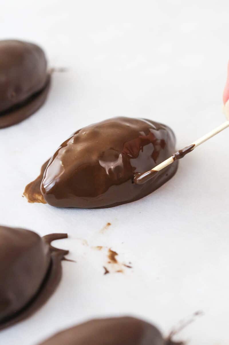 Covering the whole from the toothpick used to dip the cookie dough football in chocolate with chocolate.