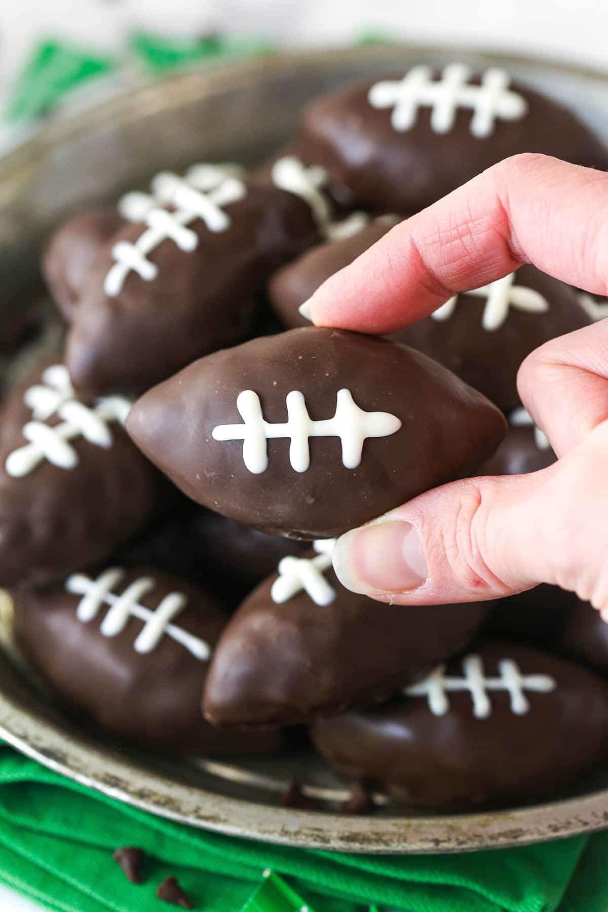 A hand holding a cookie dough football up to the camera.