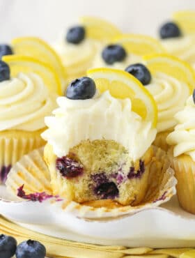 A lemon blueberry cupcake with a bite taken out of it.
