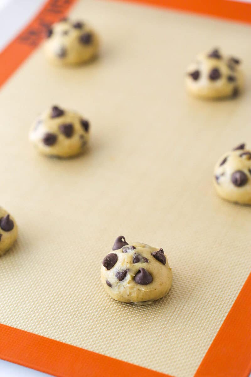 Banana chocolate chip cookie dough shaped into dough balls and arranged on a silicon baking mat.