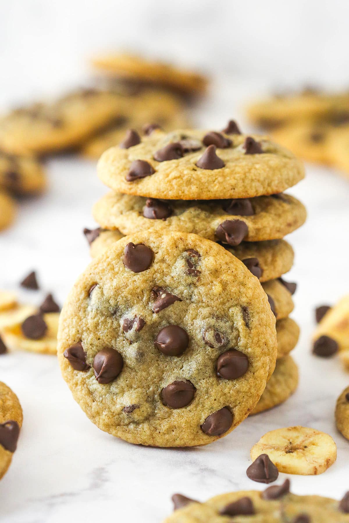 A stack of banana chocolate chip cookies with one cookie leaning against it.