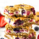 A stack of berry oatmeal cheesecake bars. The top one has a bite taken out of it.