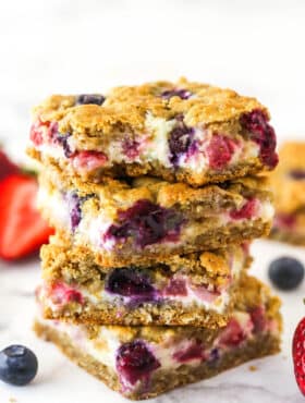 A stack of berry oatmeal cheesecake bars. The top one has a bite taken out of it.