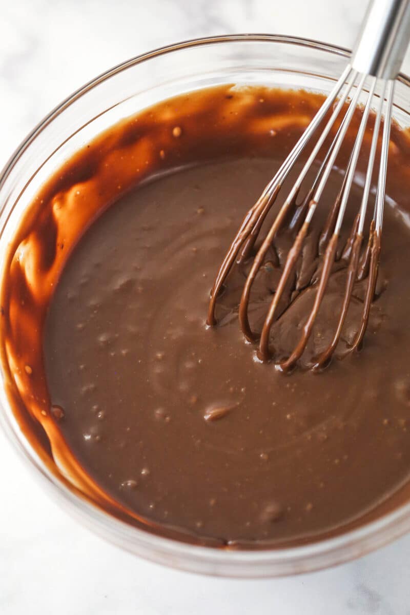 Whisking together microwaved chocolate chips and sweetened condensed milk.