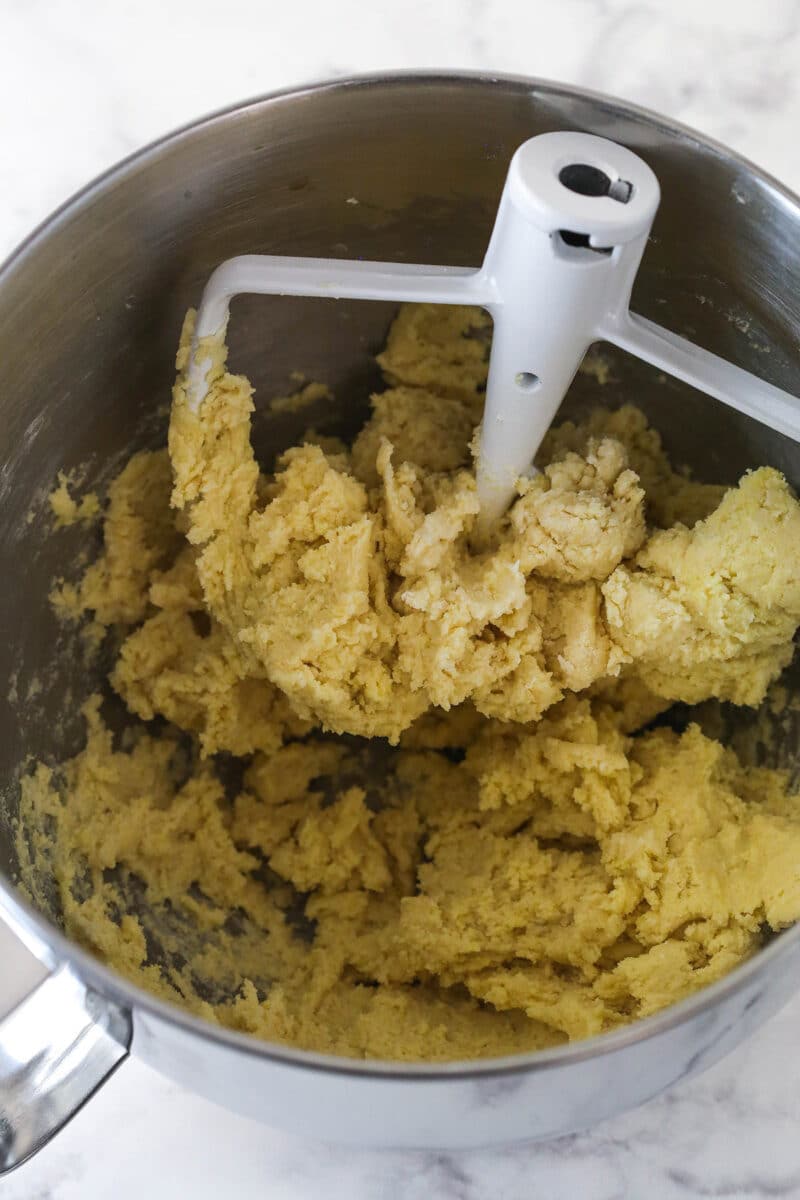 Mixing lemon pudding mix and the other dry ingredients into lemon cookie cake dough.