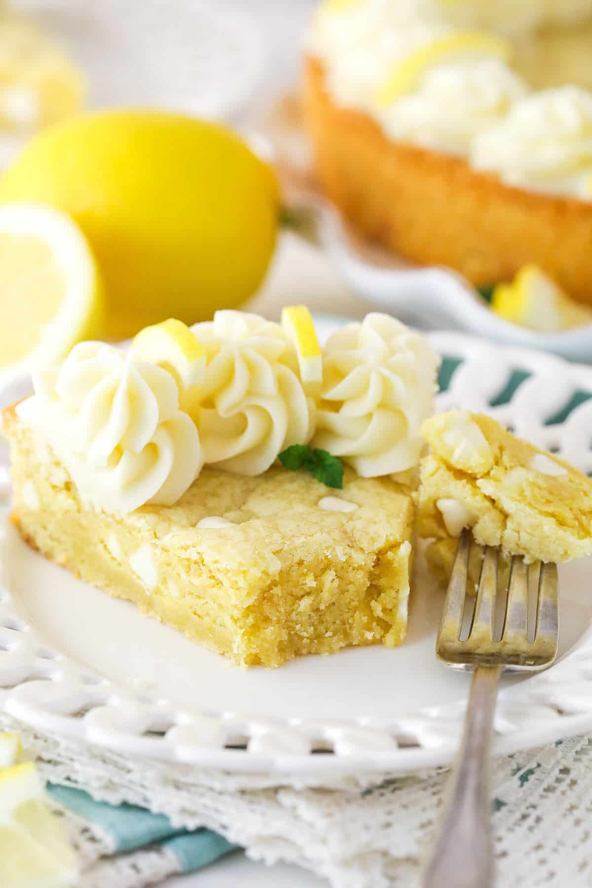 A fork taking a bite out of a slice of lemon cookie cake.