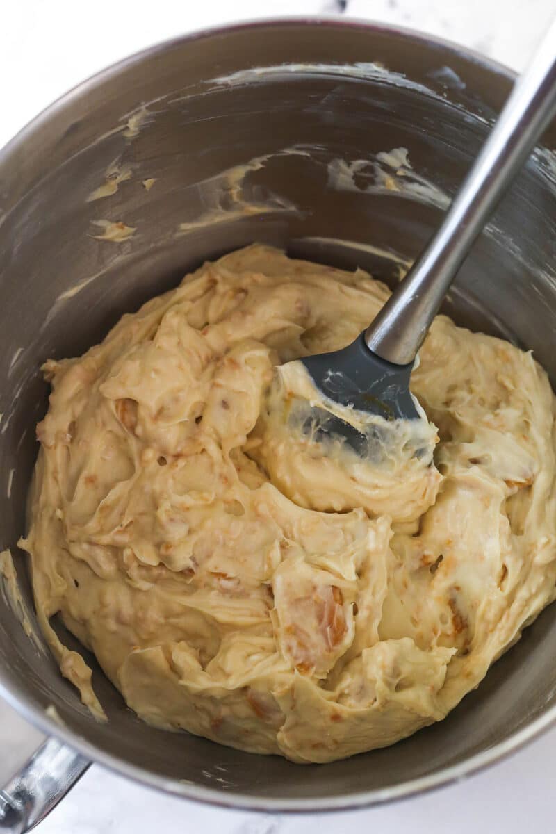 Stirring vanilla extract, coconut extract, caramel sauce, vanilla wafers, and toasted coconut into a no-bake cheesecake filling. Add volume. Whip the heavy whipping cream and powdered sugar until stiff peaks form and gently fold the whipped cream into the cream cheese base.