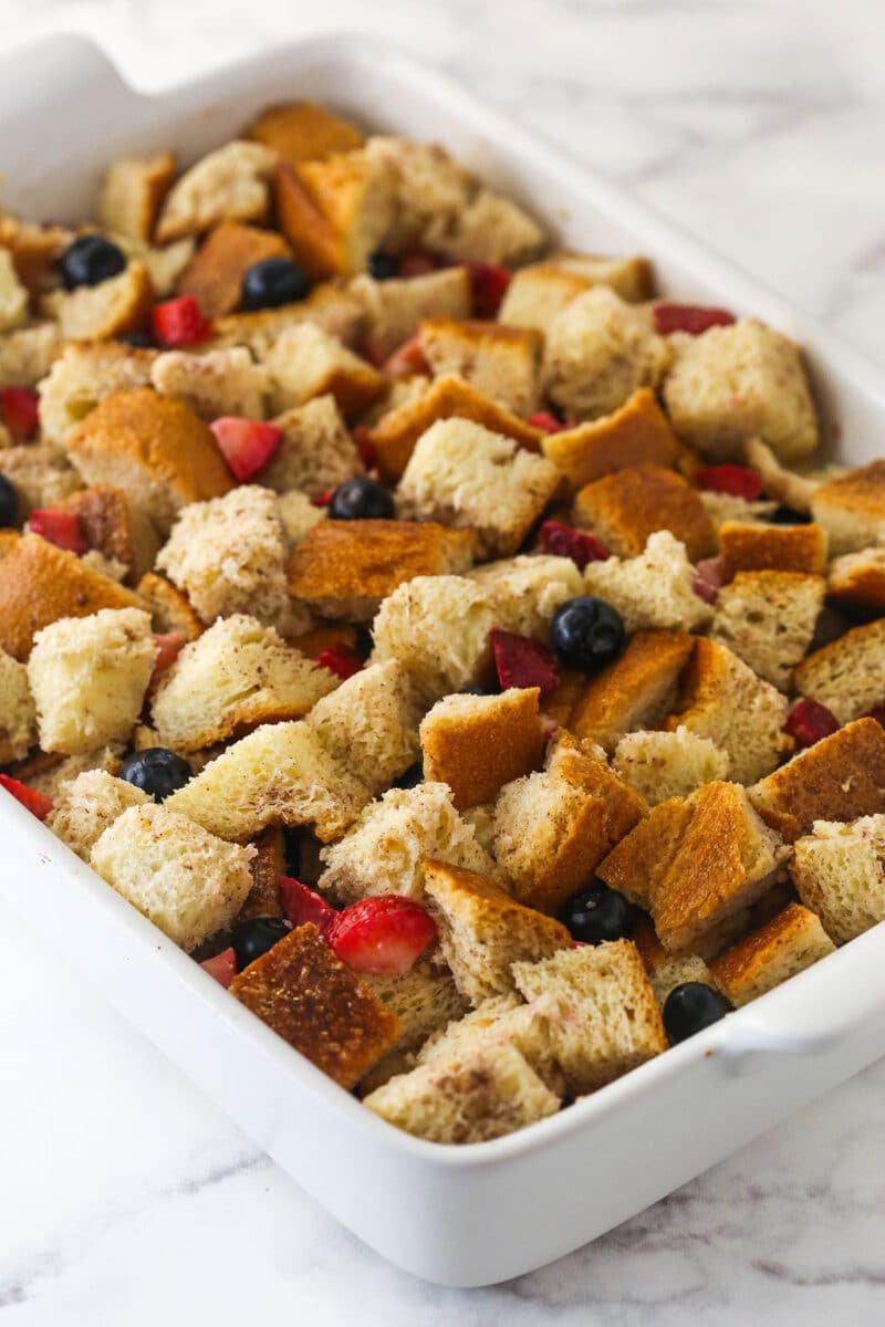 Spreading berries and cubed bread into a casserole dish.