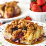 A slice of berry French toast casserole served on a plate with maple syrup.